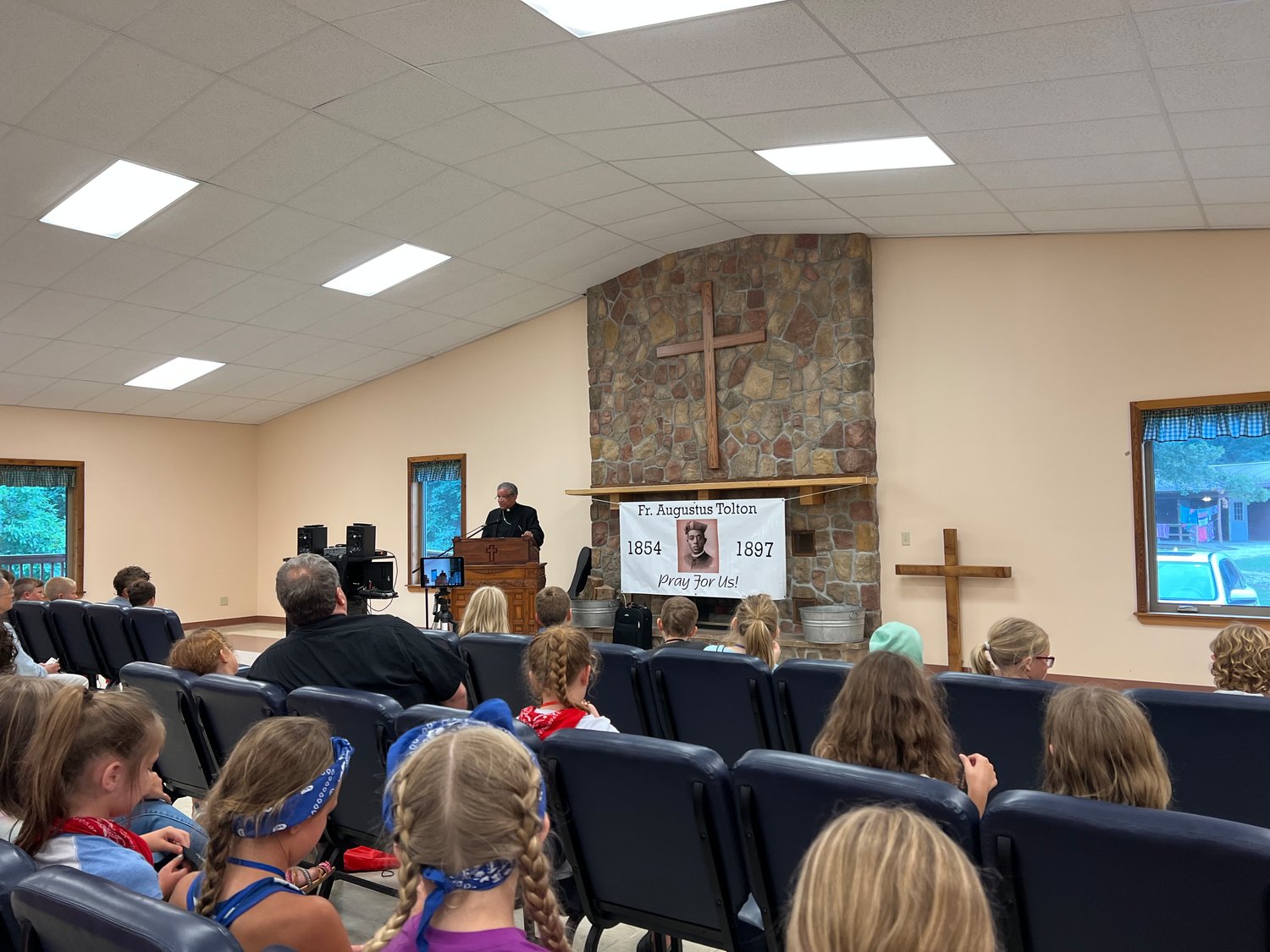 Auxiliary Bishop Joseph N. Perry of Chicago, postulator for the sainthood cause of Venerable Father Augustus Tolton, speaks to children about the life of Venerable Father Augustus Tolton during Camp Tolton at Camp Jo’Ota in Clarence.